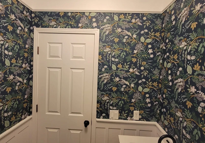 Professional wallpaper installation with dark floral pattern and seamless corners around a door frame in Colorado